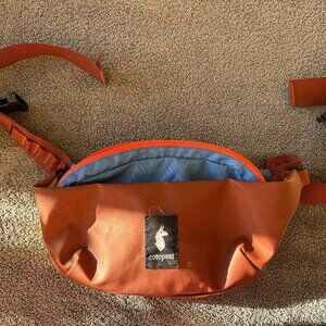 Cotopaxi coso 2L Hip pack. Features. Maroon, blue, yellow, orange.